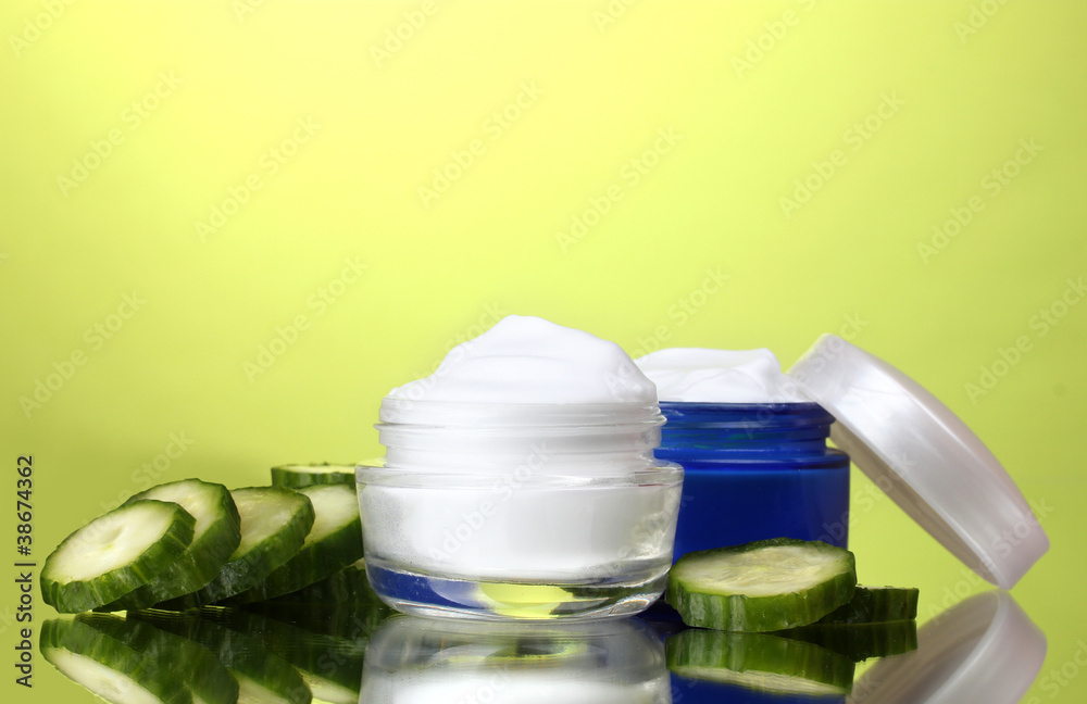 cream and fresh sliced cucumber on green background