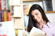 © stokkete - smiling female student with book in hands in a bookstore - model