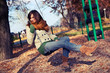 Autumn portrait of a young woman on a swing