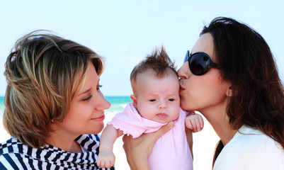 two beautiful girls with a baby on the beach