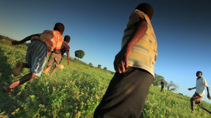 happy children playing soccer, football on the fields in africa.
