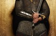 © Nejron Photo - Knight holding sword on golden background.