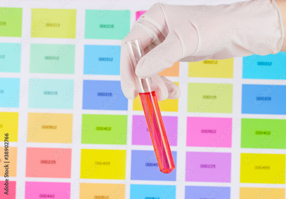 Tube with red liquid in hand on color samples background