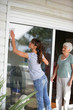 © auremar - Woman cleaning a glass patio door for an elderly lady