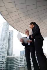 Two businesswomen stood outside high-rise building