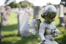 Angel With Wings Above Headstones In Cemetery
