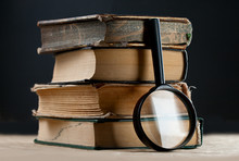 Pile Of Old Books With Magnifying Glass