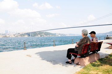 people sitting on a bench by sea