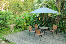 Garden Furniture - Rattan Chairs And Table Under Umbrella On A W