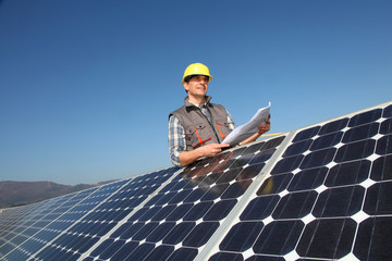 Man standing by solar panels with construction plan