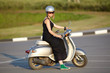 Portrait of a girl sitting on scooter wearing helmet outdoors