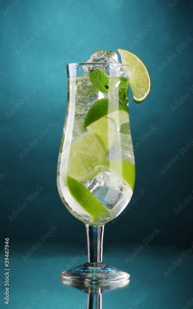 glass of cocktail with lime and mint on blue background