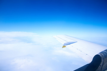 Airplane wing in the blue sky with white clouds