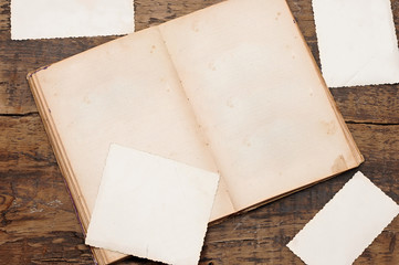 open book with blank vintage photographs on a wooden background