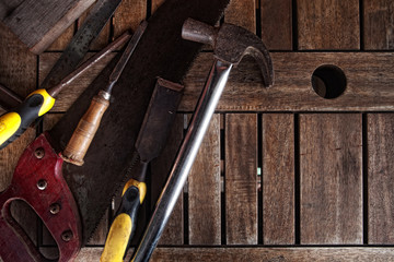 Dirty set of hand tools on a wooden panel .