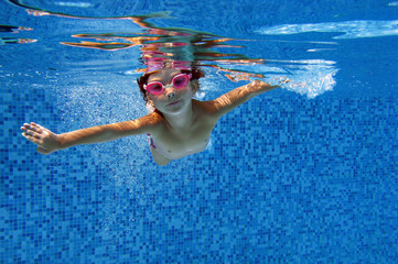 Happy child swims underwater in swimming pool. Kids sport