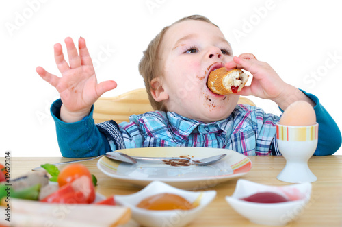 Photographie kleiner Junge beim Frühstücksbötchen essen