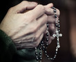 Caucasian elderly woman hands clasp Christian rosary beads in prayer