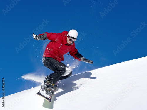 Fotografie, Obraz Snowboarder jumping through air with deep blue sky