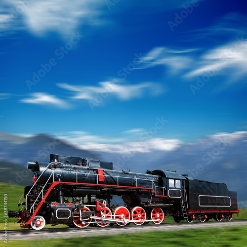 Naklejka dekoracyjna Speeding old locomotive in mountains with motion blur