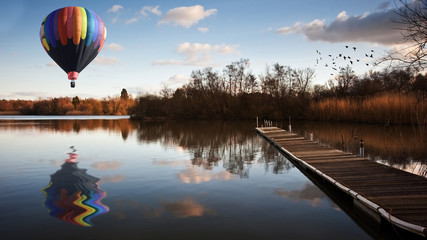 Wall Mural - Hot air balloon over sunset lake with jetty