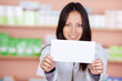 © contrastwerkstatt - junge frau in der apotheke zeigt ein schild