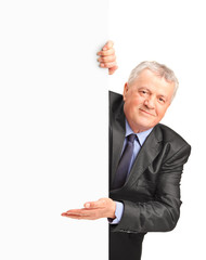 Poster - A smiling mature businessman holding a white panel and gesturing