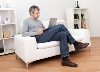 Senior man sitting in sofa and using laptop