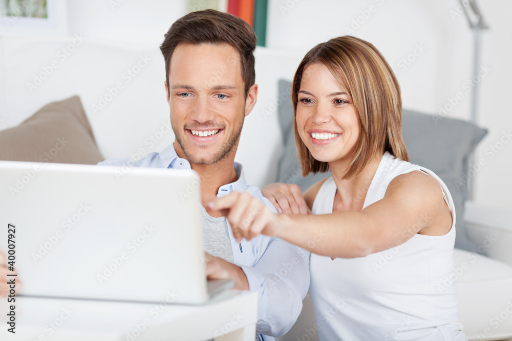 glückliches paar zeigt auf etwas am laptop