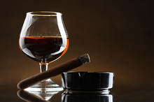 Glass Of Brandy And Cigar On Brown Background
