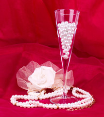 Wall Mural - White flower, pearls and beads on red background