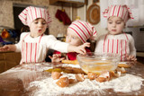Fototapeta  - Three little chefs enjoying in the kitchen making big mess. Litt