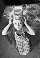 Wall Mural - little chef in the kitchen wearing an apron and headscarf