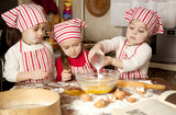 Fototapeta  - Three little chefs enjoying in the kitchen making big mess. Litt