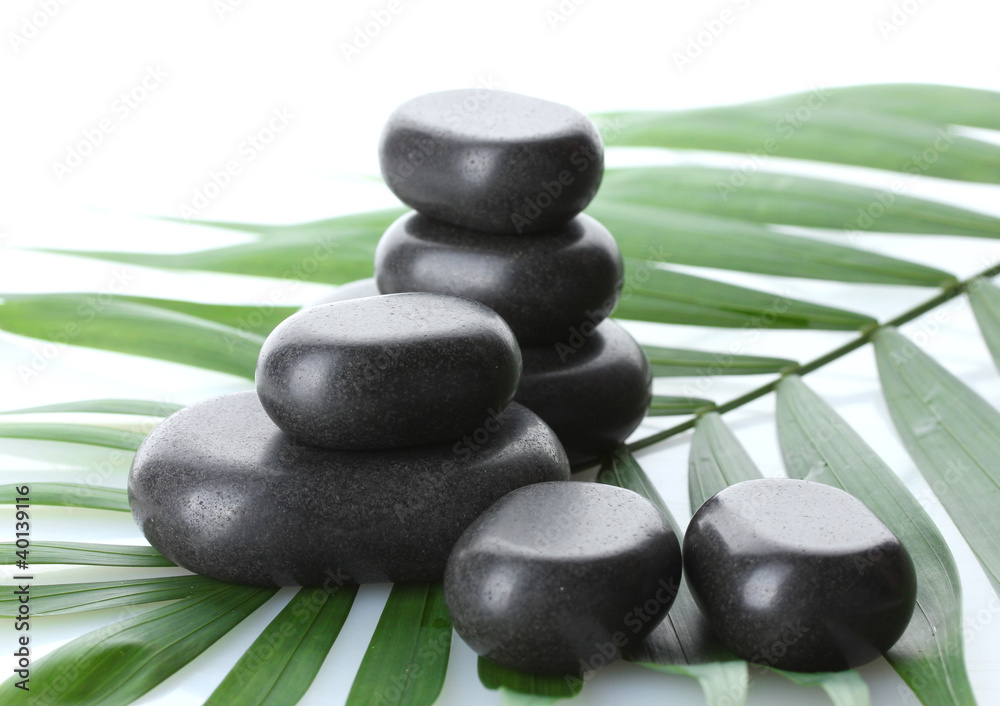 Spa stones on green palm leaf isolated on white