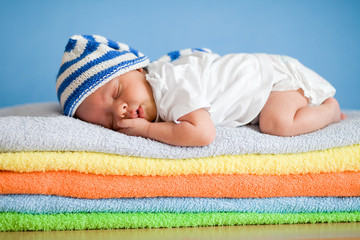sleeping newborn baby on colorful towels stack