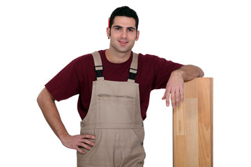 Man standing next to a wooden plank