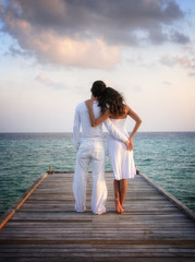 Sensual happy couple in white clothes on a pier (Maldives)