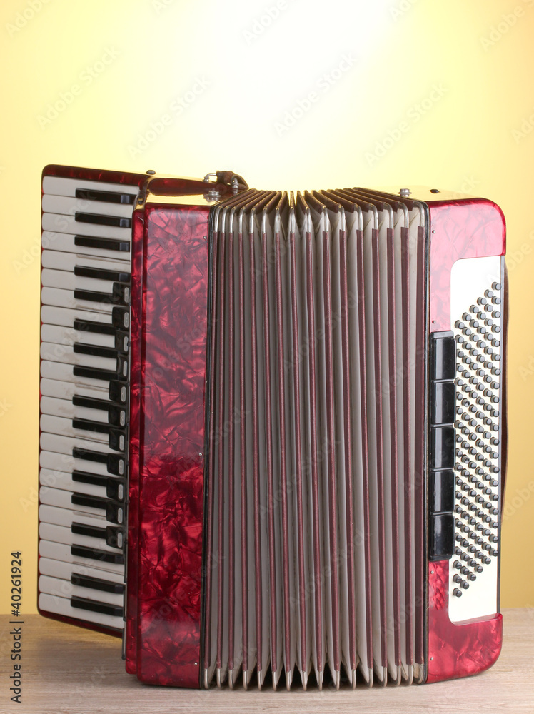 Retro accordion on wooden table on yellow background