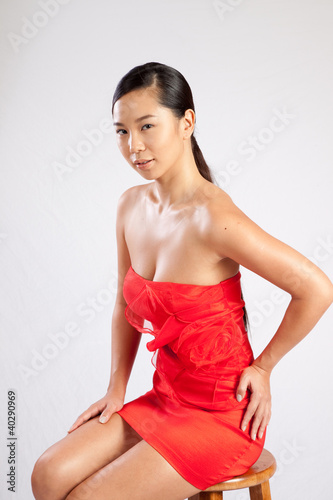 Foto Südostasiatische Frau im roten Kleid, schaut nachdenklich
