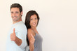 Trendy couple standing on white background with thumbs up