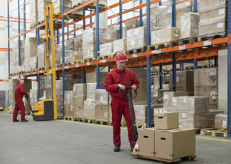 workers in uniforms and safety helmets working in storehouse