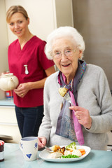 Senior woman with carer eating meal at home