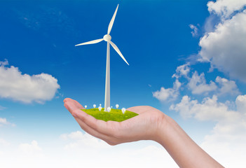 Wind turbines and light bulb on hand  over blue sky