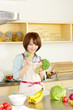 © one - Beautiful young woman in kitchen making salad