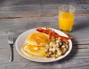 Pancakes, bacon, and hash browns on old vintage wood table