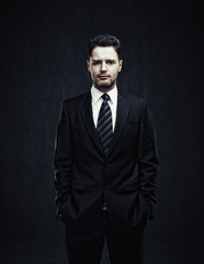 Poster - Young businessman standing with his hands in the pockets