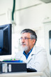 © lightpoet - Senior researcher working on a computer in a lab