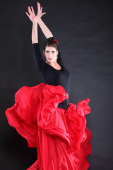 Attractive spanish young woman dancing flamenco over black backg