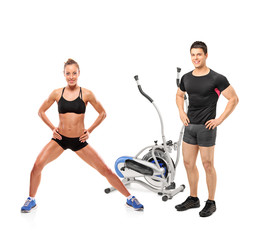 Wall Mural - Female and male athletes posing next to a cross trainer machine